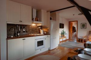 a kitchen with white cabinets and a living room at Kåseberga Hideout in Kåseberga