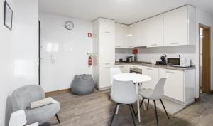 Una cocina con gabinetes blancos y una mesa y sillas. en Casa dos Barrett, en Lisboa 10 fotos más
