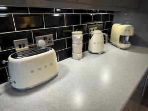 a kitchen counter with three toasters and appliances on it at Warm & Cosy, First Floor 2 Bed Central Apartment in Harrogate