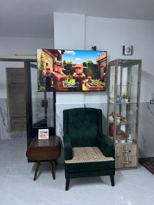 a living room with a green chair and a tv at Jarash in Jerash