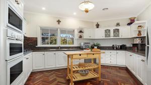 a kitchen with white cabinets and a wooden table at Southern Grace in Bowral