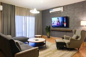 een woonkamer met een bank, stoelen en een tv bij Mabaat-White Pearl Compound 600 B Villa 3 in Jeddah