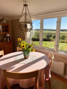 uma mesa de jantar com um vaso de flores sobre ela em Bloms stuga i naturskön miljö em Falkenberg mais 9 fotografias