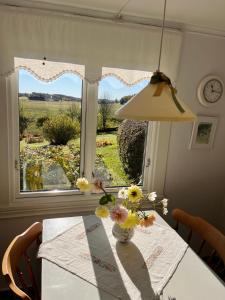 uma mesa com um vaso de flores com uma janela em Bloms stuga i naturskön miljö em Falkenberg