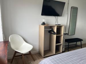 a bedroom with a white chair and a television at Mirada Do Roxo in Oia