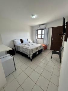 a bedroom with a bed and a chair in it at Sereia do Mar Pousada e Restaurante Ltda in Jacumã