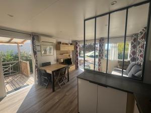 une cuisine avec une table et un salon dans l'établissement SERENITY 565 au Lac Des Rêves-camping 4 étoiles-mobil home 3ch-6pl-clim-sdb- wc séparé-au calme, belle vue sur le lac, sans vis à vis, à Lattes