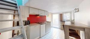 a kitchen with white cabinets and a red wall at Charmant duplex aux portes de Belfort in Bavilliers