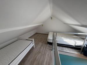 two beds in a small room with wooden floors at Charmant duplex aux portes de Belfort in Bavilliers