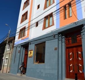 una mujer caminando por una calle en frente de un edificio en Intiqa Hotel, en Puno