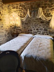 a bed in a room with a stone wall at Posada-Finca Fuentes Carrionas in Camasobres