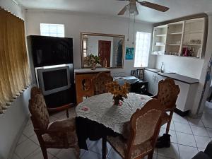 sala de estar con mesa con sillas y TV en Teal Terrace B&B, en Queensburgh