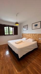 a bedroom with a large bed with white sheets at Quinta de Carvalhal - Casa de Campo in Guimarães