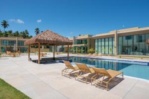 a swimming pool with chairs and a resort at Casa Milagres Morada do toque- By milagres hospitalidade in São Miguel dos Milagres