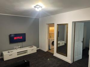 Una sala de estar con televisión y un espejo. en Cozy Apartment Hunedoara, en Hunedoara
