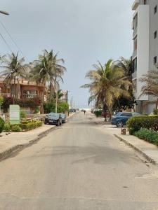an empty street with palm trees and cars parked at Saphir in Dakar
