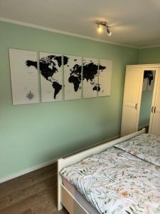 a bedroom with a bed with four maps on the wall at Eifelnest Stadtkyll in Stadtkyll