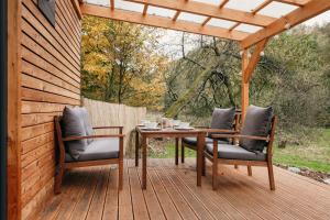 a wooden table and chairs on a wooden deck at Krušnoglamp - Tinyhouse u Řeky in Sadov