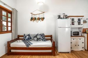 a kitchen with a refrigerator and a bed in a room at Chalé com Churrasqueira a 5min da Praia Estaleiro in Balneário Camboriú
