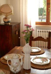 a table with a white vase with flowers in it at Villa Iliana in Lucca +50 photos