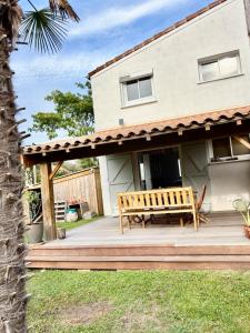a wooden bench on a deck in front of a house at Nana Bloo in La Teste-de-Buch