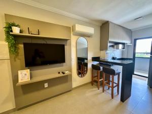 a kitchen with a tv and a bar with chairs at Studio Maia Aconchego e praticidade 190m da UFU in Uberlândia