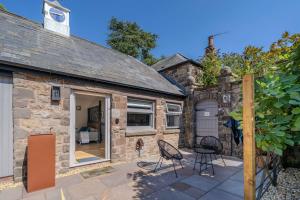 a stone cottage with a patio and chairs at Goytre Hall Self Catering Guest Accommodation in Abergavenny