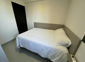 a small bedroom with a bed with white sheets at Studio Maia Aconchego e praticidade 190m da UFU in Uberlândia