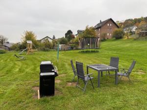 a grill and a table and chairs in a field at Eifelnest Stadtkyll in Stadtkyll