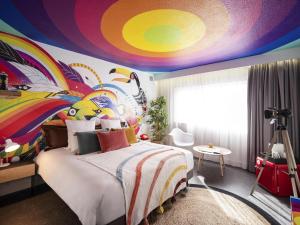 1 dormitorio con 1 cama con techo colorido en Mercure Reims Parc Des Expositions, en Reims