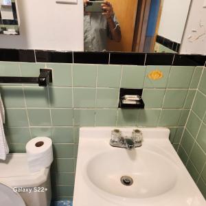 a person taking a picture of a bathroom sink at Town Inn Motel in Standish +6 photos