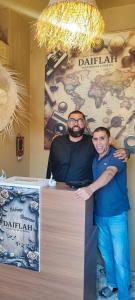 two men are standing at a table in a booth at Chambre partagée Hostel DAIFLAH in Oulad Rguia