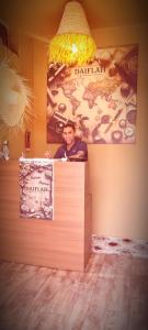 a man standing behind a counter with a sign at Chambre partagée Hostel DAIFLAH in Oulad Rguia