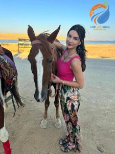 a woman standing next to a brown and white horse at كامب واحة الغروب in Dār as Salām