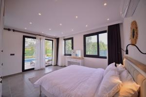 a bedroom with a large white bed and windows at Villa Matisse & Sierra - Kayaköy in Belen +45 photos