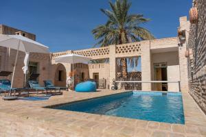 una casa con piscina y una palmera en Dar Aron - Tozeur, en Tozeur