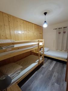 Ce lit se trouve dans un dortoir doté de 2 lits superposés et de murs en bois. dans l'établissement Les Arolles, à La Norma