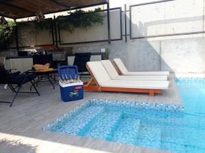 a pool with a couch and a chair next to a swimming pool at Maya House Cieneguilla in Cieneguilla +1 photo
