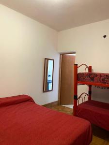 a bedroom with a red bed and a mirror at Alojamiento Don Carmelo in Fiambala