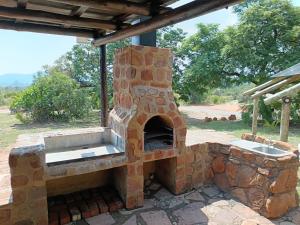 an outdoor pizza oven sitting under a roof at Cosy Cottage in Buffelspoort