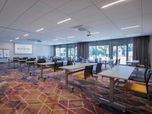 ヴロツワフにあるNovotel Wrocław Cityのテーブルと椅子と窓のある広い部屋
