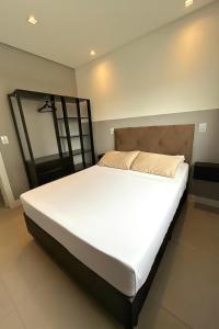a bedroom with a large bed with white sheets at Apto Home & Club em Capão da Canoa in Capão da Canoa