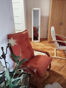 a living room with a red chair and a mirror at Apartman Andric in Valjevo