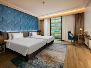 a hotel room with two beds and a desk at Mövenpick Living West Hanoi in Hanoi