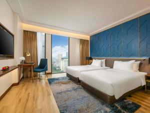 a hotel room with two beds and a large window at Mövenpick Living West Hanoi in Hanoi
