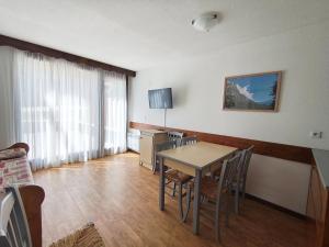 a room with a table and chairs and a television at Les Balcons de la Vanoise in La Norma