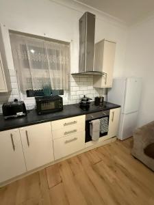 a kitchen with white cabinets and a black counter top at Spacious Stay in the Heart of the Town in Moffat +9 photos