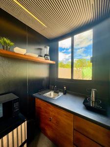 a kitchen with a sink and a microwave and a window at TinyHouse OASIS con Jacuzzi&Cenote&Piscina in Telchac Puerto