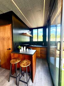 a kitchen with a counter and two stools at TinyHouse OASIS con Jacuzzi&Cenote&Piscina in Telchac Puerto