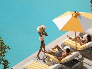 Una mujer con sombrero camina por una piscina en Delano Dubai at Bluewaters, en Dubái